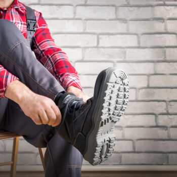 Buider,Putting,On,Shoes,For,Work,Near,Brick,Wall.,Safety