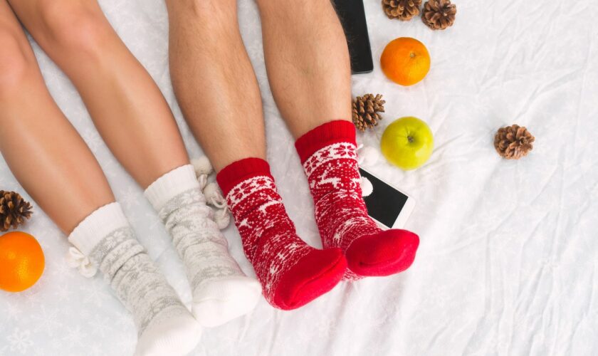 soft-photo-woman-man-bed-with-phone-fruits-top-view-point-female-male-legs-couple-warm-woolen-socks_155003-21534