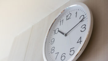 White,Metal,Clock,On,Wooden,Wall,With,Warm,Light,In