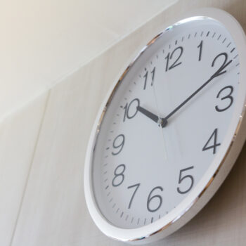 White,Metal,Clock,On,Wooden,Wall,With,Warm,Light,In